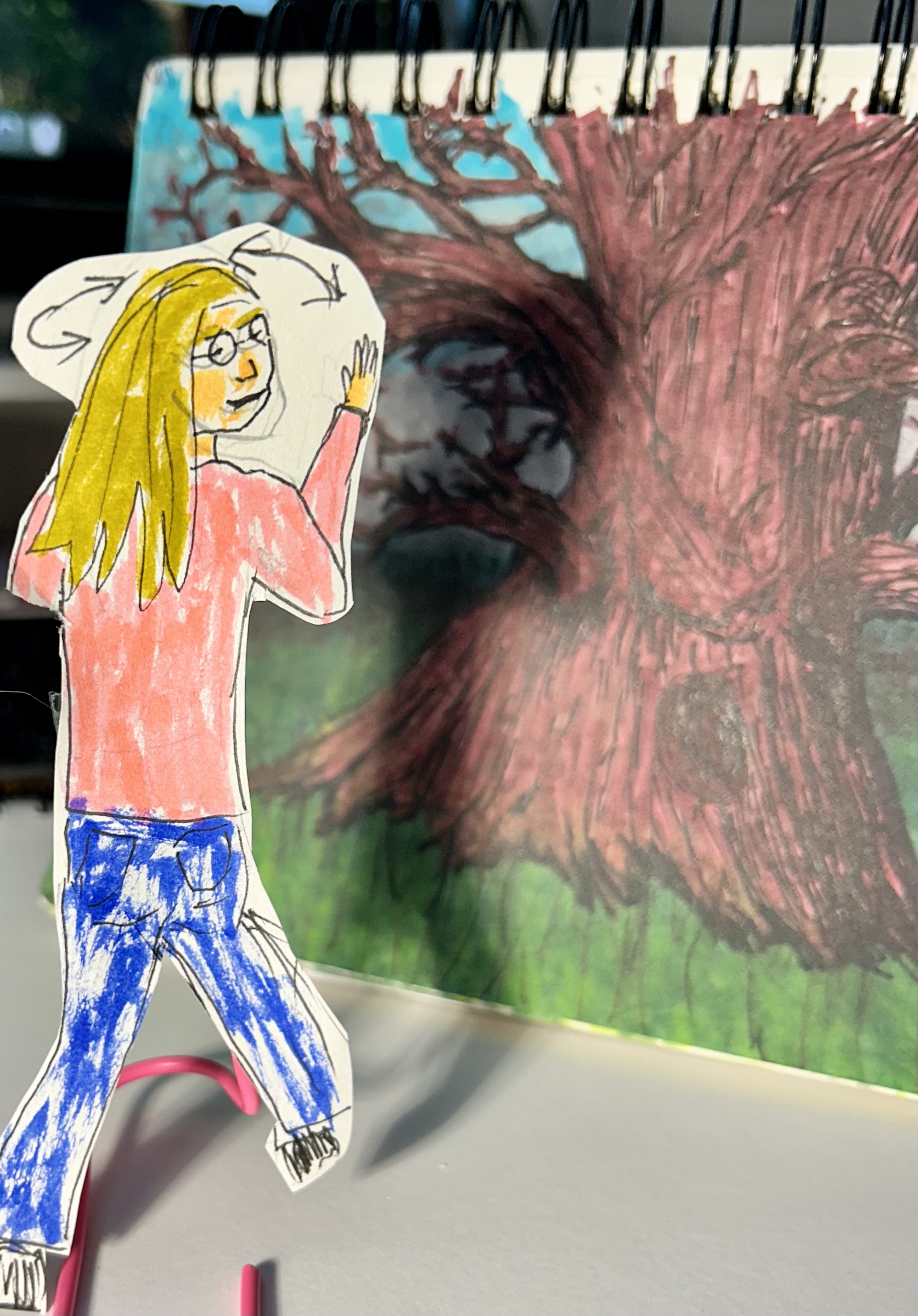 A paper cutout of Anne is positioned in front of an open notebook as if entering it.